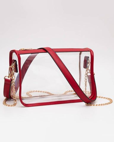 Clear handbag with red frame and gold chain strap on a white background