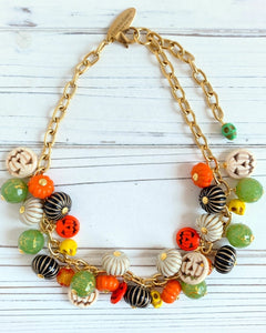 Colorful beaded necklace with gold chain on a white wooden surface