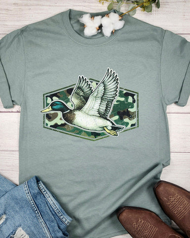 Green t-shirt with a duck graphic on a wooden surface with jeans and boots.